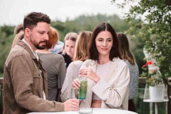 Pärchen steht mit Drinks am Stehtisch