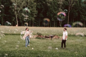 Pärchen spielt auf der Wiese mit riesigen Seifenblasen