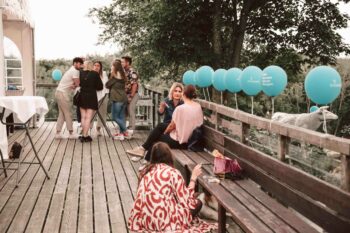 Terrasse mit türkisen Ballons und Personen im Gespräch