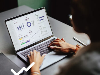 Hände tippen auf Macbook, Screen zeigt Statistiken und Diagramme