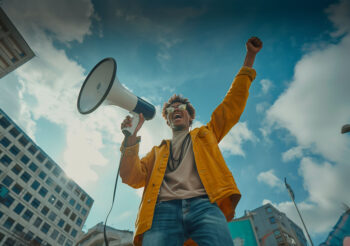 Junger mann schreit in ein Megaphone, Hochhäuser im Hintergrund