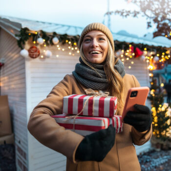 Frau hält Geschenke und Smartphone in der Hand